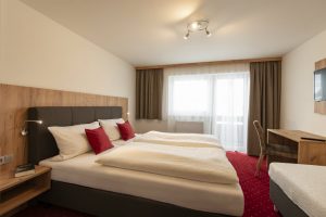 Hotelzimmer roter Teppich antracietes bed und Moebel aus Holz