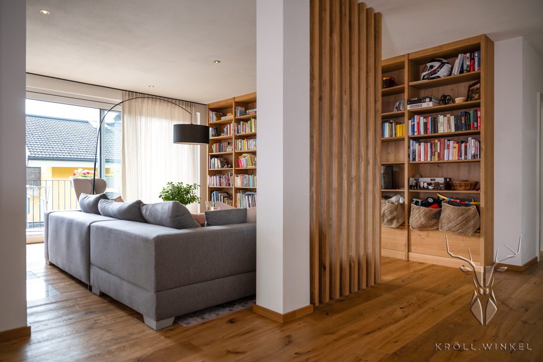 Wohnzimmer mit Bücherregal und Holztrennwand aus Eiche