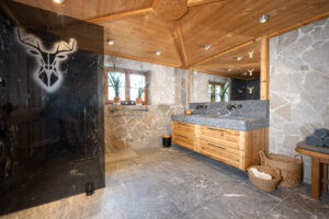 Chalet Badezimmer. grauer Duschwand. Rustikaler Naturstein mit Eichen Altholz