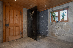 Badezimmer Interieur. Naturstein. Dunkler Glaswand. Eichentür und Decke.