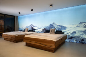 Wellness-Relax-Bett aus Eiche mit dahinter eine Fotoleinwand mit winterlicher Berglandschaft.