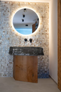 Massives Waschbecken aus Naturstein auf Eichenfuß mit Perlmutt-Rückwand.