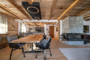 Chalet Interieur. Kücheninsel mit Natursteinplatte und integrierter Eichentisch. Massiver Steinkamin.