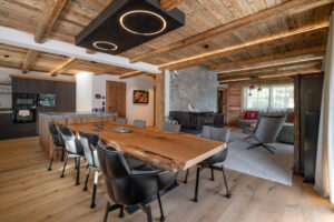 Chalet Interieur. Kücheninsel mit Natursteinplatte und integrierter Eichentisch