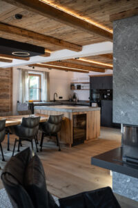 Chalet Interieur. Kücheninsel mit Natursteinplatte und integrierter Eichentisch