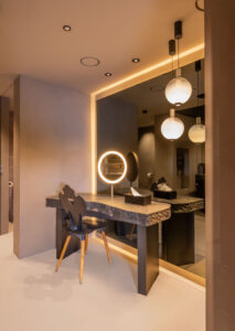 Dunkler, beleuchteter Ganzkörperspiegel mit Umrandung hinter massivem Steintisch.