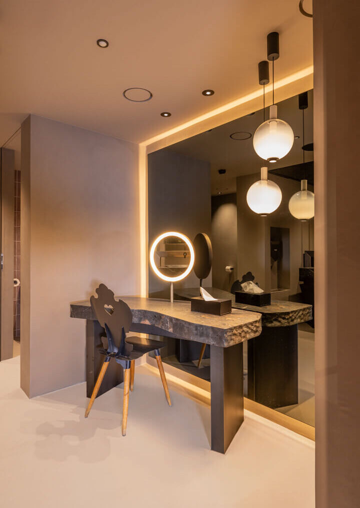 Dunkler, beleuchteter Ganzkörperspiegel mit Umrandung hinter massivem Steintisch.