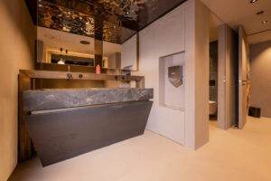 Hotel-chiques Badezimmer mit massivem Steinwaschbecken, kupfernen Armaturen und verspiegelter Decke.