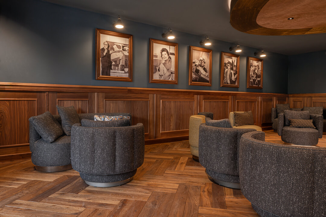 Elegantes Kaminzimmer, Fischgrätboden, Holz-Lambrisierung an den Wänden im englischen Stil. Beleuchtete Beleuchtete Schwarz-Weiß-Porträts.