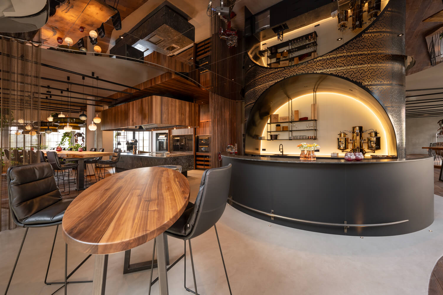 Luxuriöse Hotel-Showküche mit Naturstein, Nussholz, Eichentisch und beleuchteter Bar