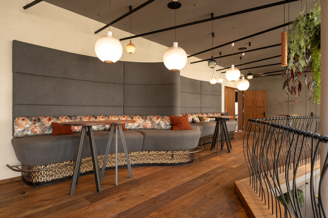 Moderne Sitzlandschaft mit langer grauer Bank und Hochtischen