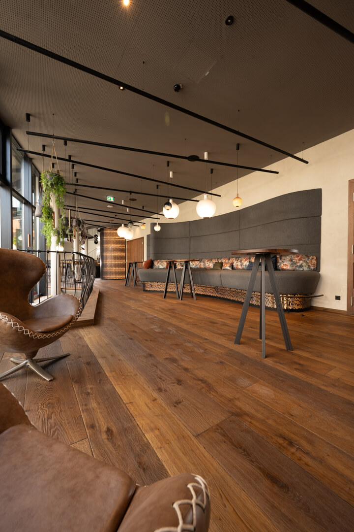 Moderne Sitzlandschaft mit langer grauer Bank und Hochtischen