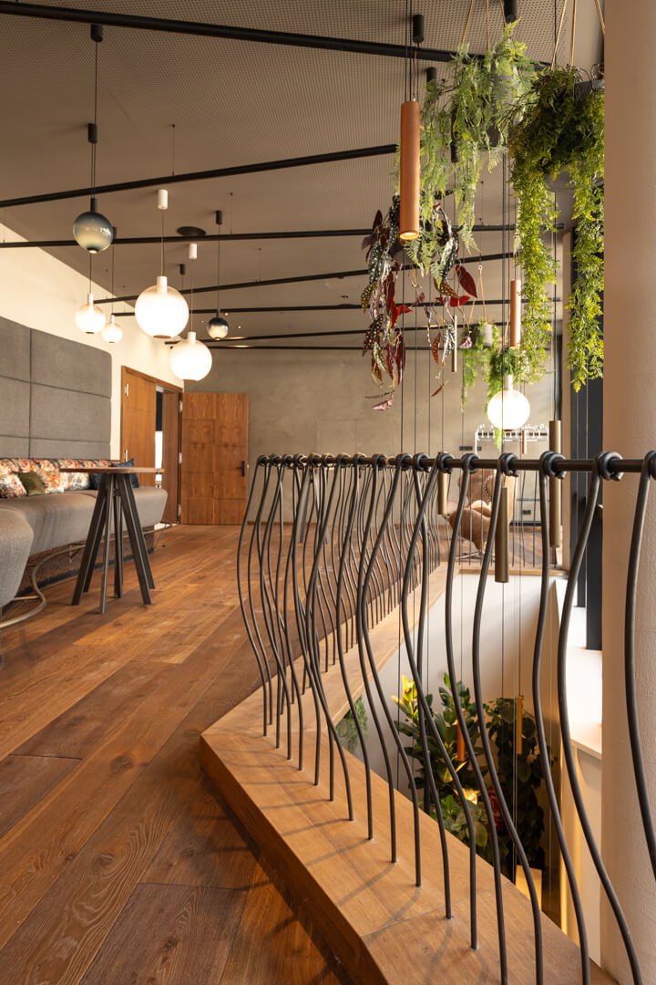 Moderne Sitzlandschaft mit langer grauer Bank und Hochtischen. Stahlgeländer.