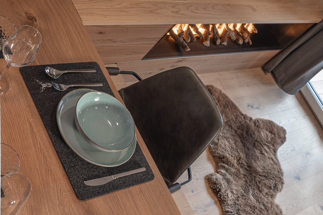 Gedeckter Eichentisch vor einem modernen Gaskamin.