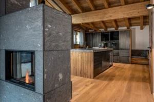 Chalet massiver Naturstein Kamin und Stahllook Küche mit Eichen Fronten