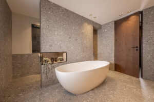Badezimmer Marmorierte Ivory-Fliesen. Freistehene Badewanne.