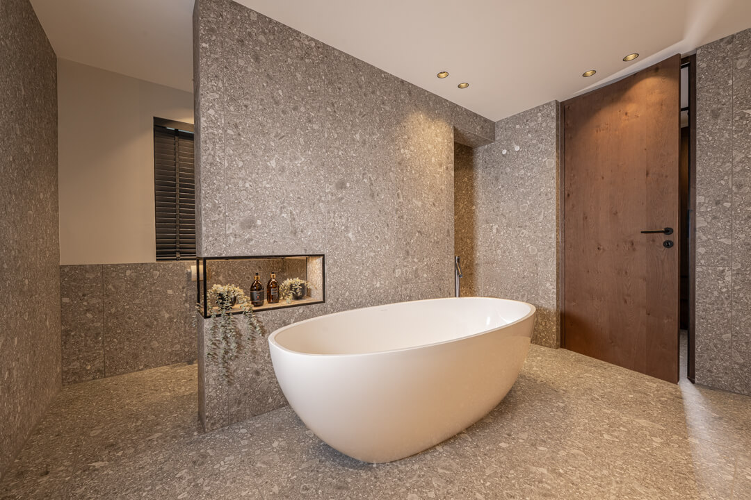 Badezimmer Marmorierte Ivory-Fliesen. Freistehene Badewanne.