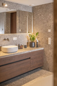 Badezimmer Möbel dunkles Holz und marmorierte Ivory-Fliesen.