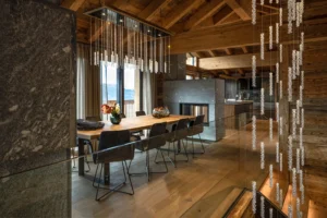 Chalet Eszimmer mit Esstisch. Swarovski Leuchte und Steinkamin