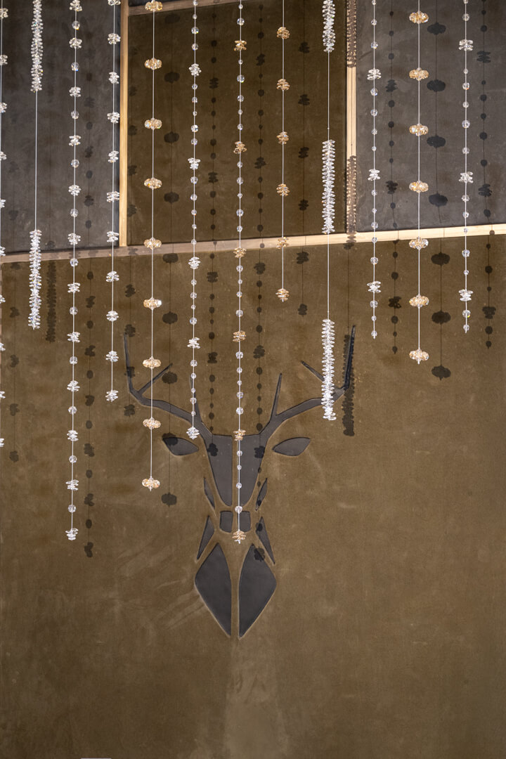 Lederwand mit Hirschmotiv und dekorativen Swarovski-Pendants.“