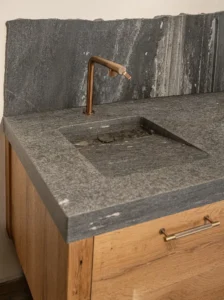 Massive anthrazitfarbene Stein-Arbeitsplatte mit ausgefrästem Waschbecken. Eichenmöbel & Goldenen Griffen