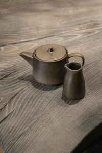 Schwarze Porzellan-Teekanne auf verkohltem Holztisch
