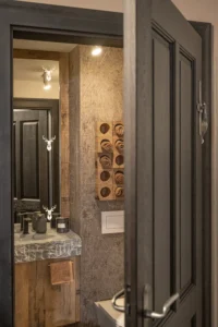 Badezimmer mit dunkler Tür, Altholzmöbel und Steinwaschbecken