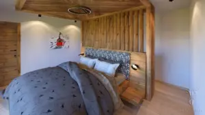 Luxuriöses Chalet-Schlafzimmer mit Kingsize-Holzbett, Wandvertäfelung aus Holz und Fischgrät-Holzdecke.